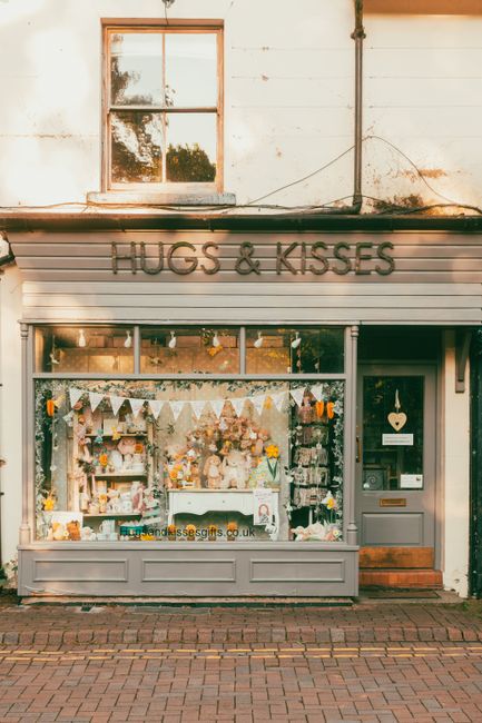 The storefront of a charming floral shop named 'Hugs & Kisses' on Tilehouse Street Hitchin, featuring a large display window filled with an assortment of fresh flowers, bouquets, and decorative orname