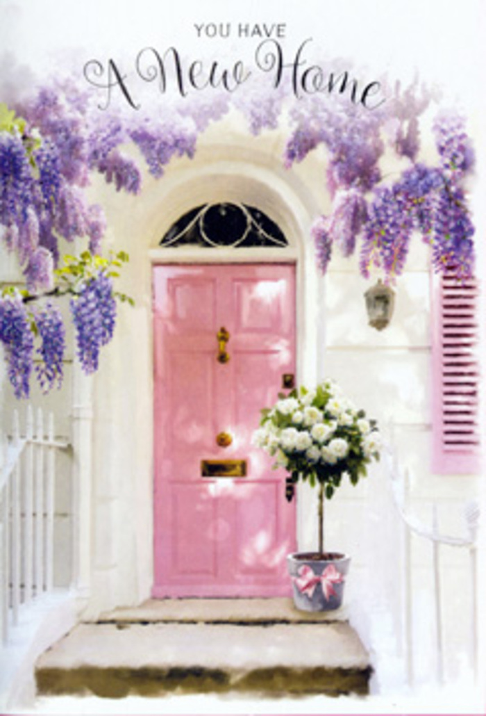 This scene feels like stepping up to a new front door on a peaceful Hitchin side street, perhaps just off Sun Street or close to the cobbled market square, arms full of anticipation and a heart full of nerves. The door itself is painted a soft, rosy pink, the kind of shade that glows warmly in natural light and offers instant reassurance as you approach. Above, wisteria trails down in lavish curtains of lavender and soft purple, its clustered blossoms forming a fragrant canopy that frames the entrance with a romantic, storybook charm. The whitewashed wall and coordinating pastel shutter extend the calm, airy palette, allowing the flowers to take centre stage while still giving a sense of lived-in character. At the threshold, a stylish grey metal bucket is placed with intention, holding an armful of white and creamy roses that almost spill over the rim. The roses are full and plush, their layered petals unfolding like little clouds, interlaced with sprigs of fresh green foliage that add depth and texture. A satin bow in blush pink cinches the base of the bucket, small but significant, echoing the colour of the door and tying the whole composition together. You can almost sense the delicate fragrance rising up-rose sweetness mingling with wisteria's powdery perfume, carried on the kind of gentle breeze that travels across Hitchin's open green spaces. The atmosphere is one of hopeful transition: a perfect floral snapshot for a housewarming gift, celebrating not just bricks and mortar but the friendships, dinners, and memories that will soon gather behind that welcoming pink door.