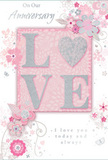 This anniversary card is presented like a softly lit still life, its design echoing the romance of a pastel bouquet delivered to a cosy home in Hitchin. At the centre, the word LOVE is set in bold, raised letters, each one delicately coated in fine glitter so that they shimmer gently, not with loud sparkle but with a refined, pearly sheen. The tactile quality is clear, as though the letters have been gently embossed, encouraging fingers to trace the sentiment. Around this, the background unfolds in tender shades of blush pink, creamy white, and misty silver, creating a calm, harmonious setting reminiscent of an early-morning sky over the nearby countryside. Stylised flowers and curling leaves weave across the card, forming loose garlands that frame the central word. Their petals are drawn with precision and softness, combining blush tones, pale greys, and clean whites, while subtle silver details highlight their shapes like a fine metallic thread running through a bouquet ribbon. The floral motifs feel airy and light, drifting across the card rather than sitting in rigid lines, much like a romantic arrangement of garden-style flowers. The artwork is carefully balanced so the eye moves naturally from the glittering text through the floral swirls and back again, without any one area feeling heavy. Inside, an elegant script carries heartfelt anniversary messages, complementing the graceful exterior. Overall, the card's soft colours, delicate textures, and thoughtful composition create an impression of enduring affection, perfect for couples marking another shared year in Hitchin with flowers, a card, and quiet gratitude.